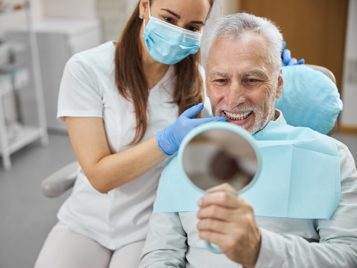Woman smiling and holding a dental implant model, showing proper care and healing after implant surgery at Bay of Isles Dental