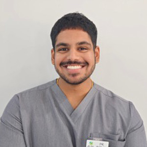 Dr Ronan smiling in a professional headshot wearing dental scrubs.