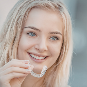 woman holding clear aligner with straight teeth after orthodontic treatment